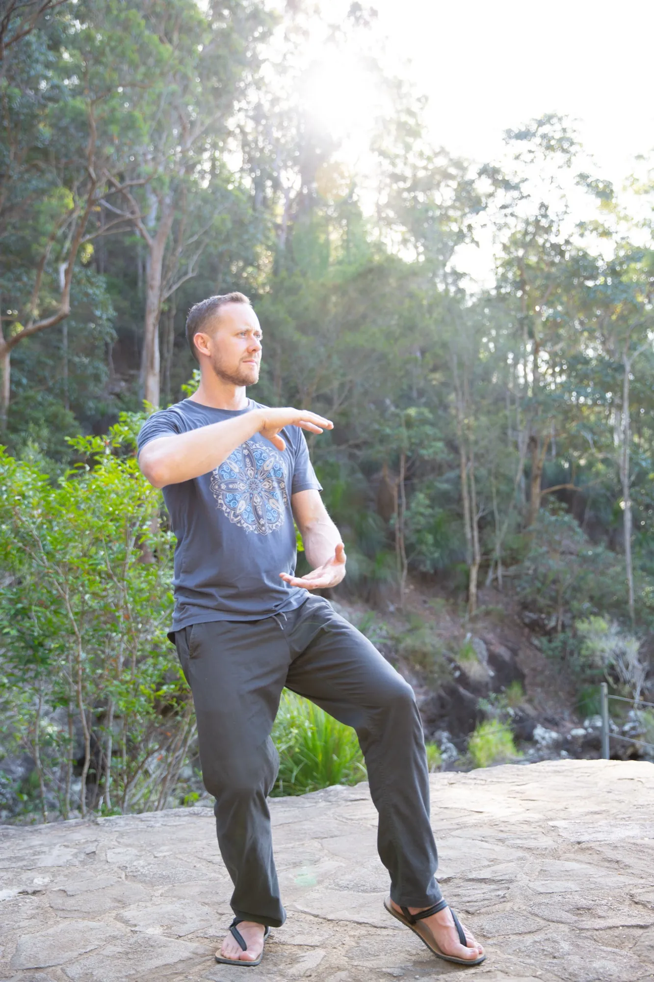 Ross in crane stance, backlit by the sun through trees