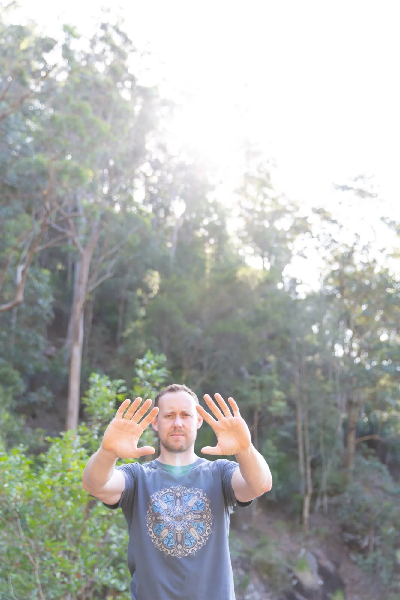Ross Parkinson, hands raised, bush backdrop